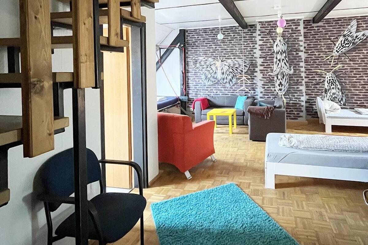 A modern interior with a staircase, a blue rug, and a brick wall with hanging decorations.