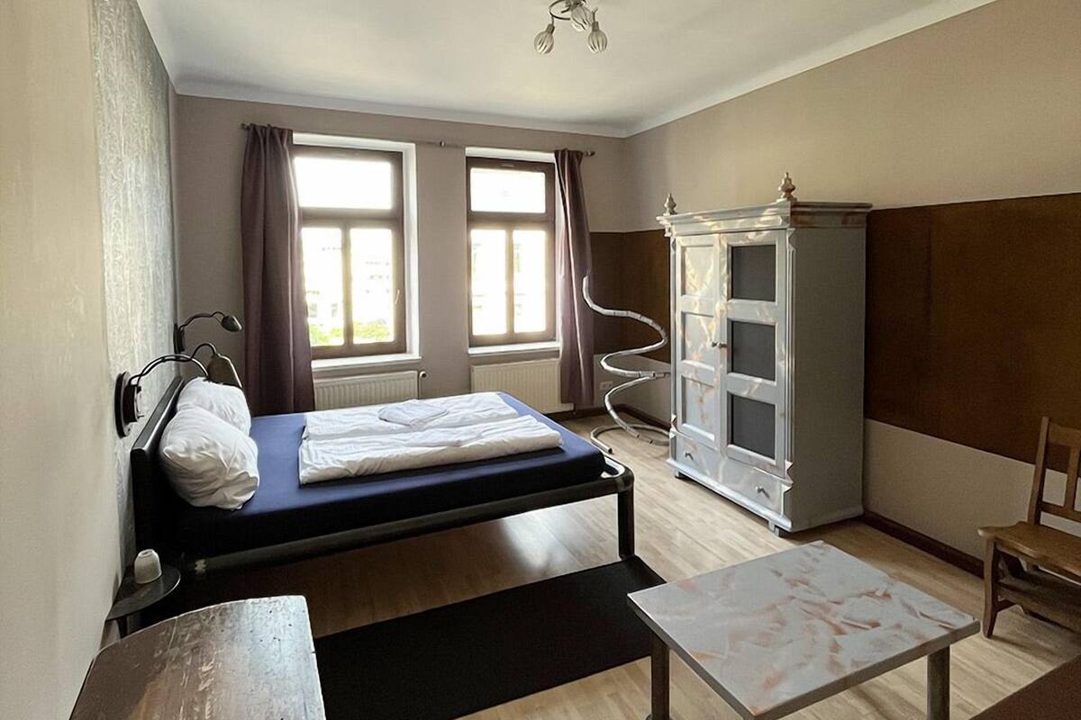 A compact room with a bed, a desk, a cabinet, and a chair.