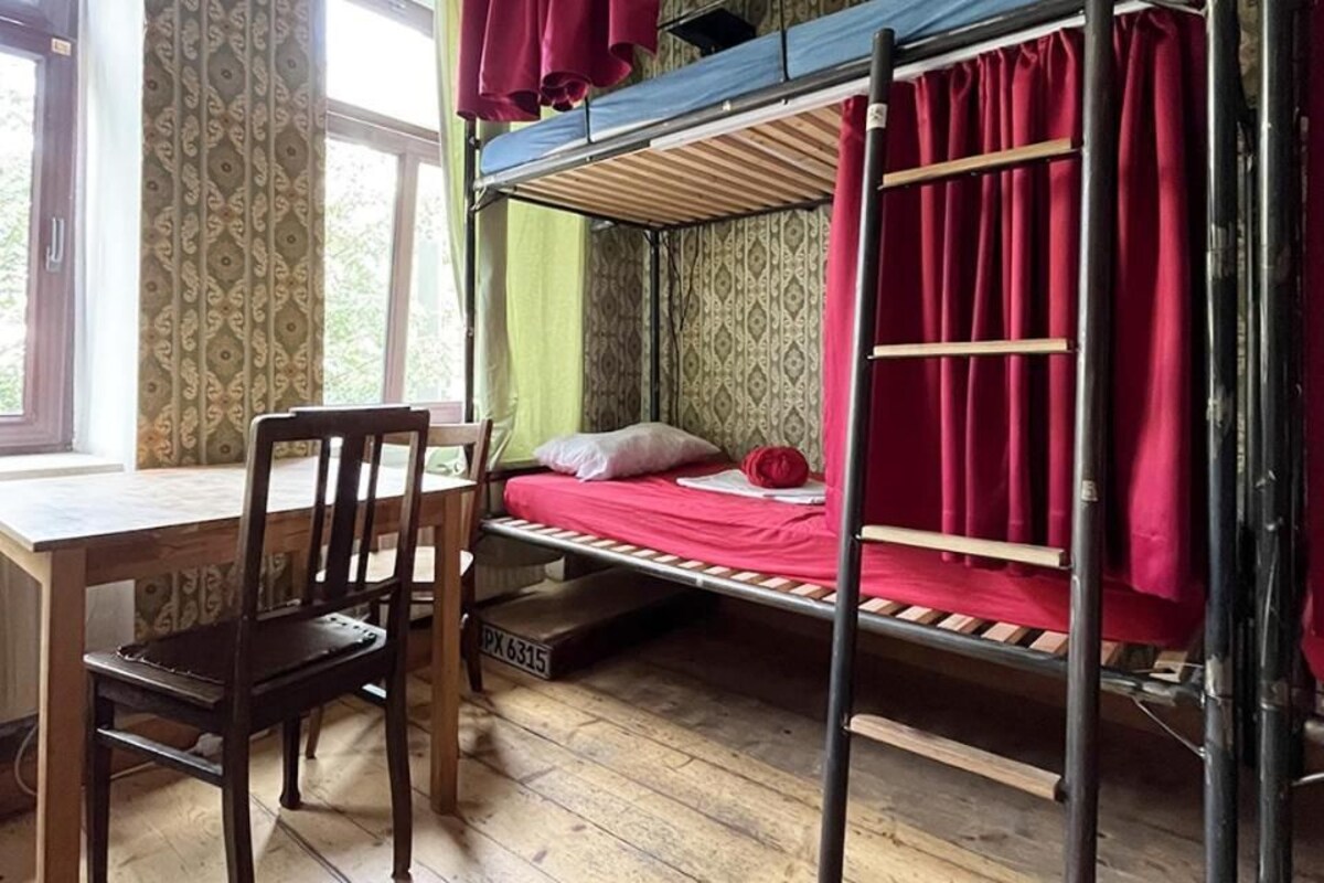 Una cama litera con escritorio y silla, una ventana con cortinas y un papel tapiz estampado.