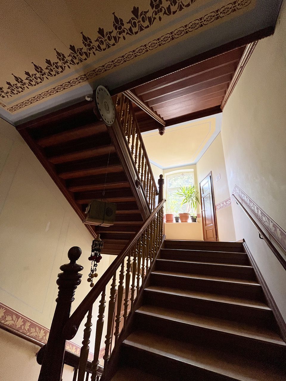 Una escalera de madera con techo decorativo y un reloj.