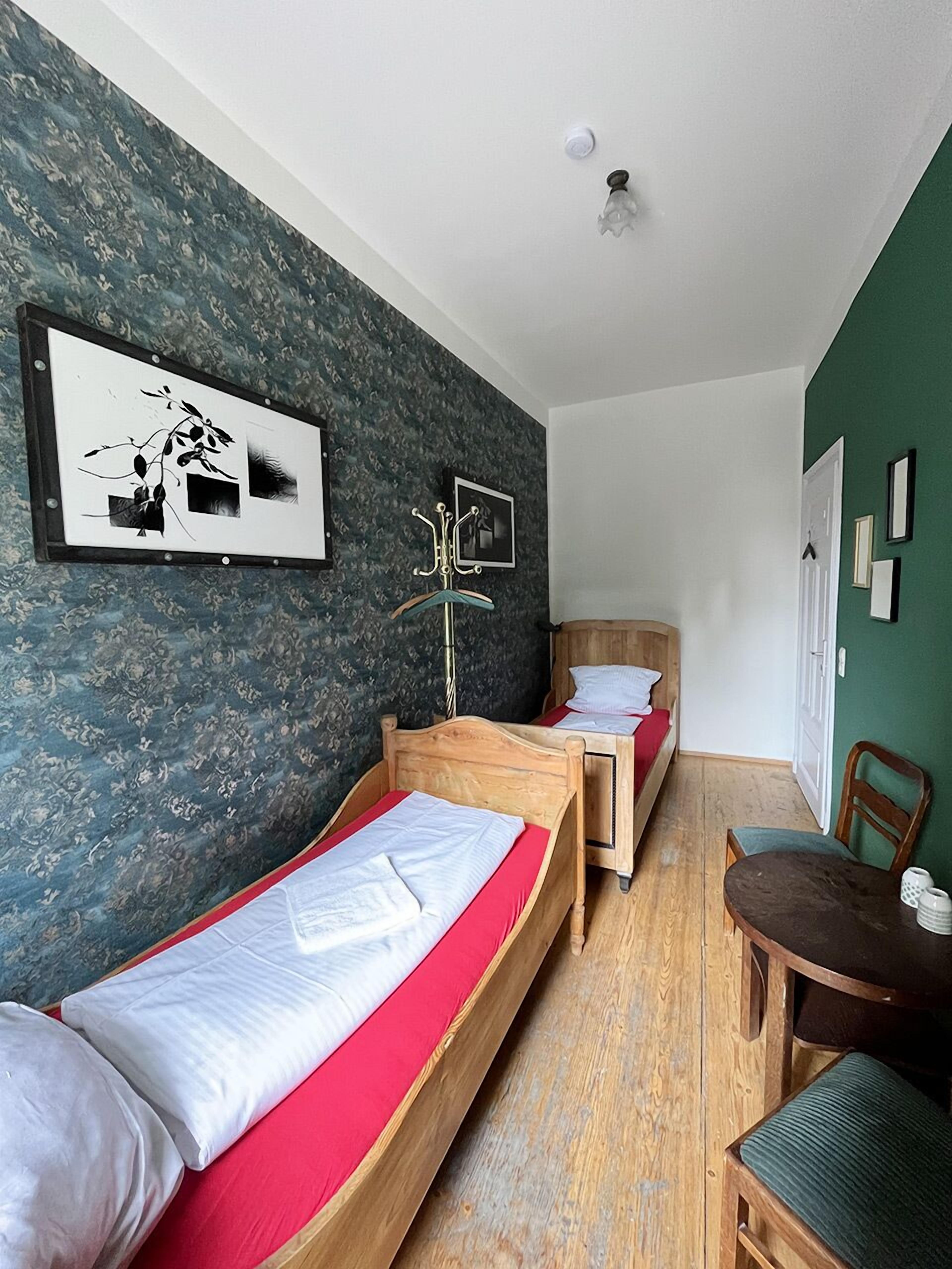 Una habitación con dos camas de madera, una mesa de madera y una silla.