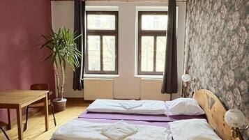 Une chambre à coucher avec un lit en bois, deux fenêtres, un bureau et une plante en pot.