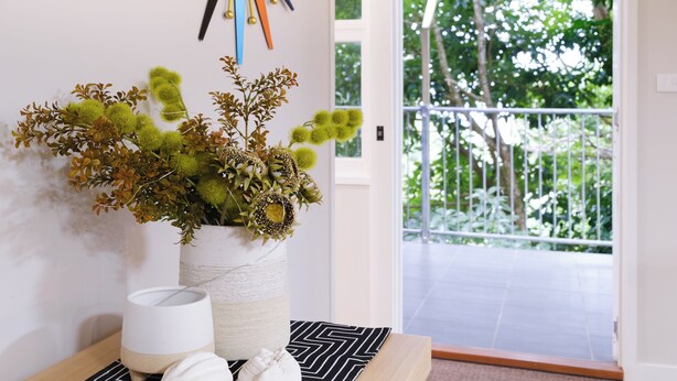 A hallway with a decorative wall clock, a potted plant, and a wooden bench. - The Point. A rainforest and ocean view retreat (Flying Fish Point)