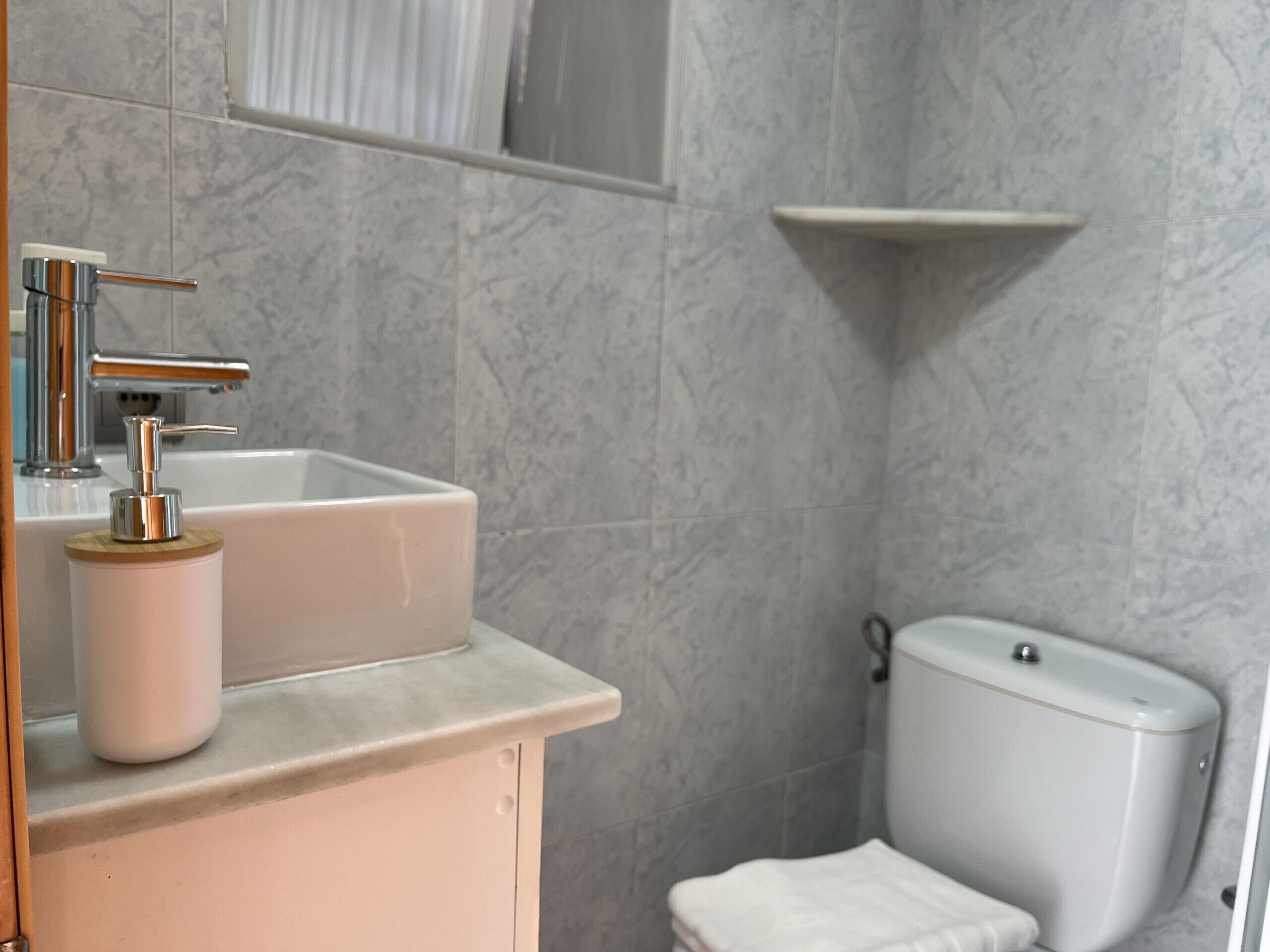 A bathroom with a white sink, chrome faucet, and a toilet.