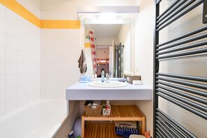 Un baño con un lavamanos blanco, un espejo y un estante de madera debajo.