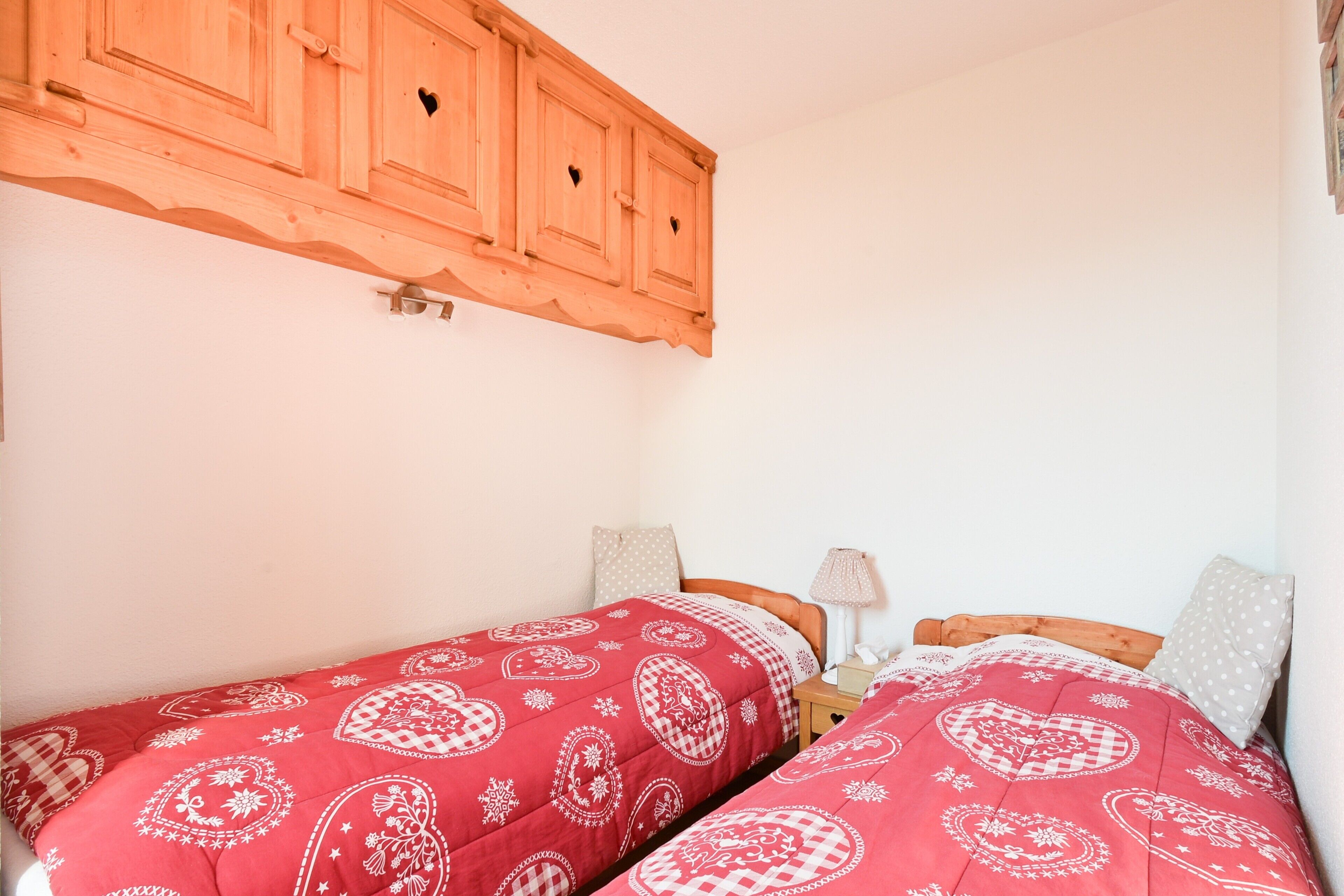 Un dormitorio con dos camas, cabecero de madera y un aparador de madera encima.