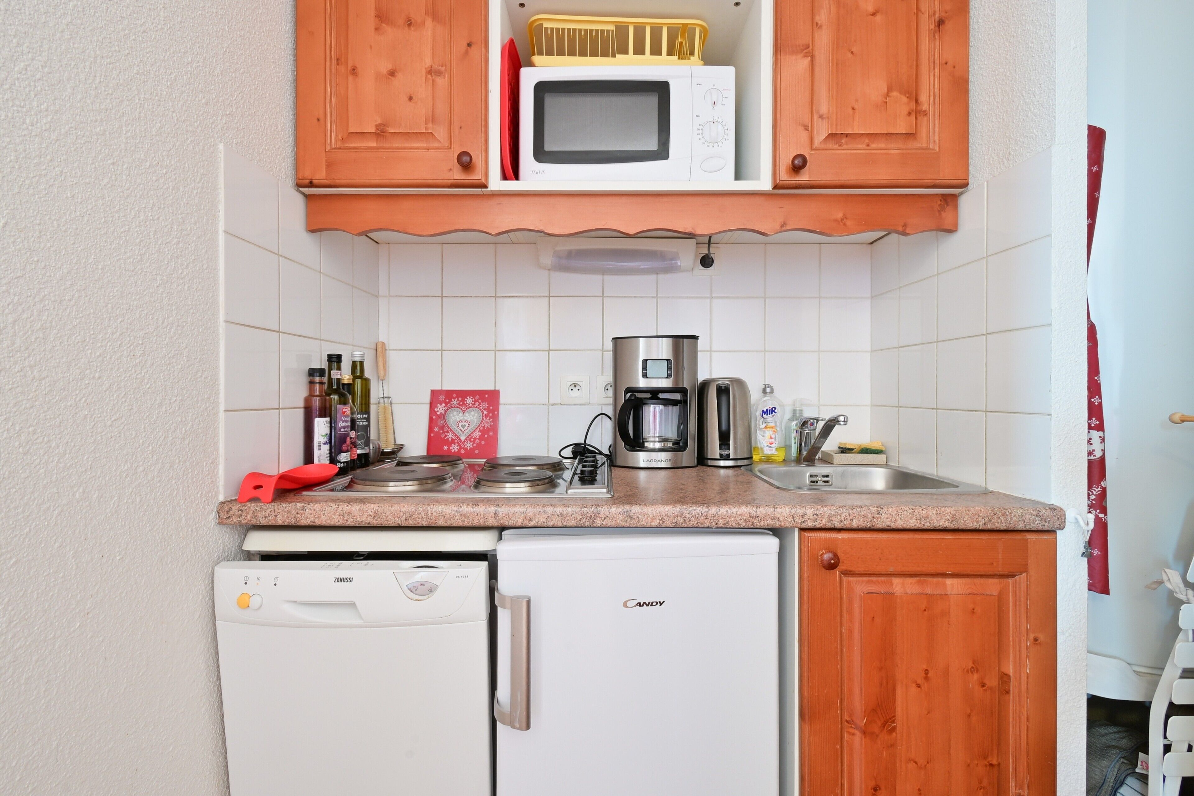 Eine kleine Küche mit Mikrowelle, Kaffeemaschine und Geschirrspüler.