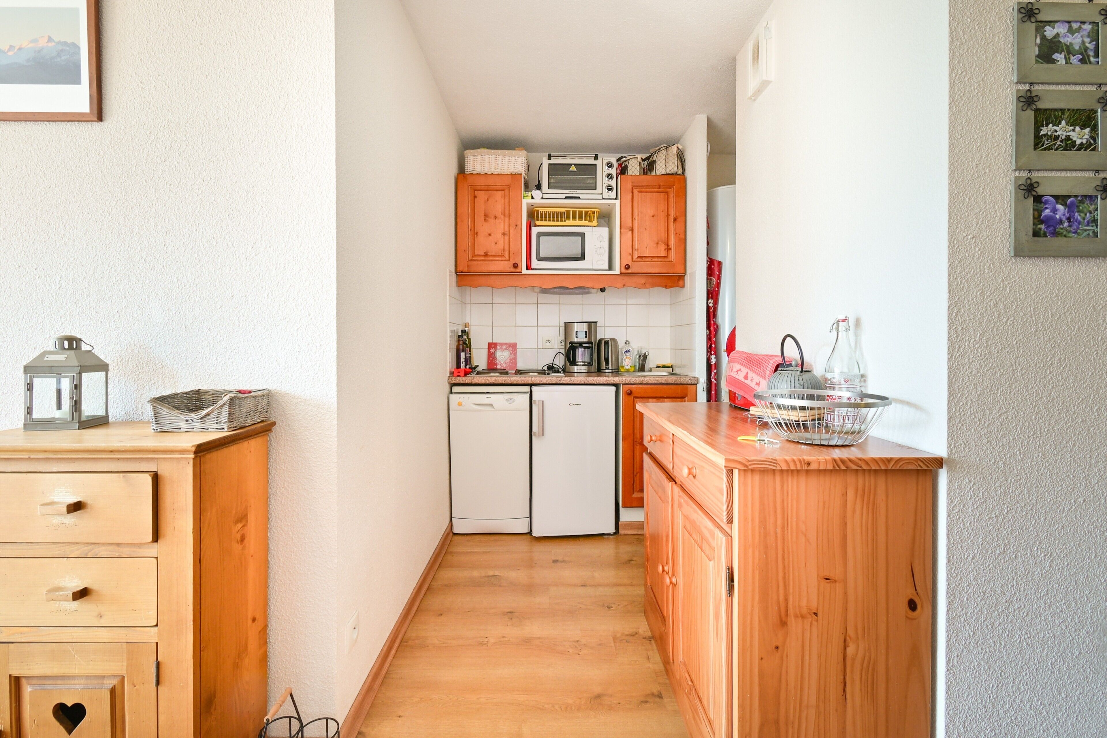 Une cuisine étroite avec des meubles de rangement en bois, un four à micro-ondes, une machine à café et un lave-vaisselle.