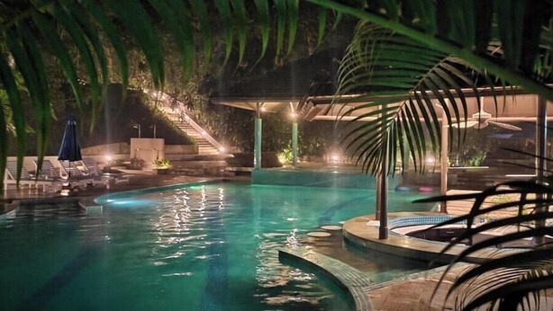 Ein Swimmingpool mit Whirlpool, Liegestühlen und einer Treppe, die zu einem überdachten Bereich führt.