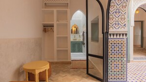 A hallway with a herringbone floor, a wooden bench, and a tiled area with geometric patterns. - Riad du Musée - Private boutique riad - 3 beds - jacuzzi (Marrakech)