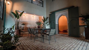 A dining area with a patterned floor, a table with chairs, and a decorative wall with a patterned design. - Riad du Musée - Private boutique riad - 3 beds - jacuzzi (Marrakech)
