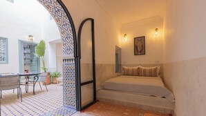 A bedroom with a bed, a small table, and chairs in a courtyard with patterned flooring. - Riad du Musée - Private boutique riad - 3 beds - jacuzzi (Marrakech)