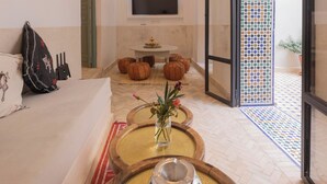 A modern living room with a sofa, a TV, and a decorative wall. - Riad du Musée - Private boutique riad - 3 beds - jacuzzi (Marrakech)