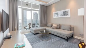A modern living room with a sectional sofa, a coffee table, and a TV. - Vogue Damac Prive Walk to Dubai Mall (Dubai)