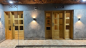 A building facade with three wooden doors, each with glass panels, and stone walls. - Volcanoes Over View Safaris & Camp  (Kinigi)