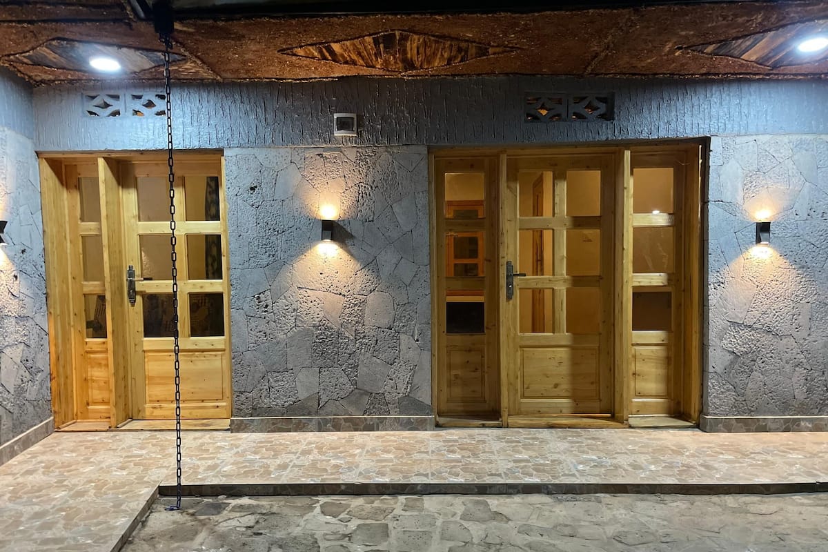 A building facade with three wooden doors, each with glass panels, and stone walls.