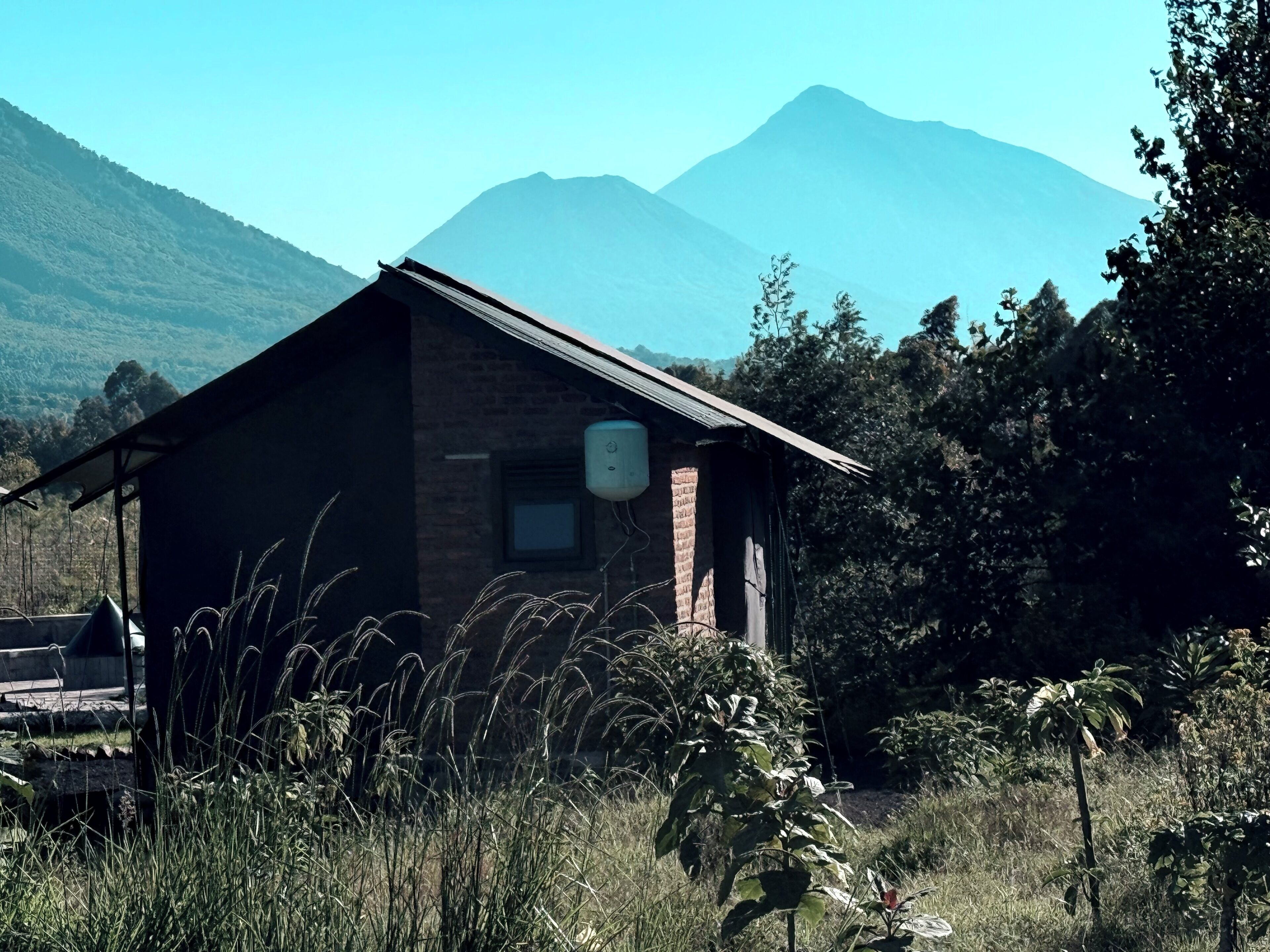 A rustic cabin with a brick exterior, a small window, and a water tank on the roof.