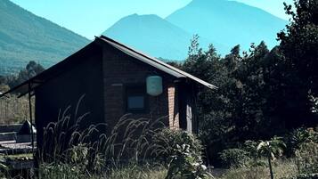 A rustic cabin with a brick exterior, a small window, and a water tank on the roof.