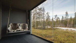Une pièce dotée d’une grande fenêtre, d’un tapis en fourrure et offrant une vue sur une forêt.