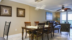 A dining area with a wooden table and chairs, a chandelier, and a ceiling fan. - Oceanfront Escape -  1007 Towers Grande (Daytona Beach Shores)