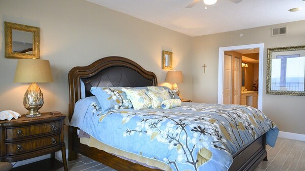 A bedroom with a bed, nightstands, lamps, a mirror, and a cross on the wall.