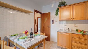 A kitchen with wooden cabinets, a granite countertop, and a dining table set for four. - Lake Garda Home - 3BR With Balcony Views (Riva del Garda)
