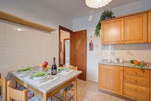 A kitchen with wooden cabinets, a granite countertop, and a dining table set for four. - Lake Garda Home - 3BR With Balcony Views (Riva del Garda)