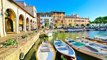 A canal with boats docked, a row of colorful buildings, and a clear blue sky.