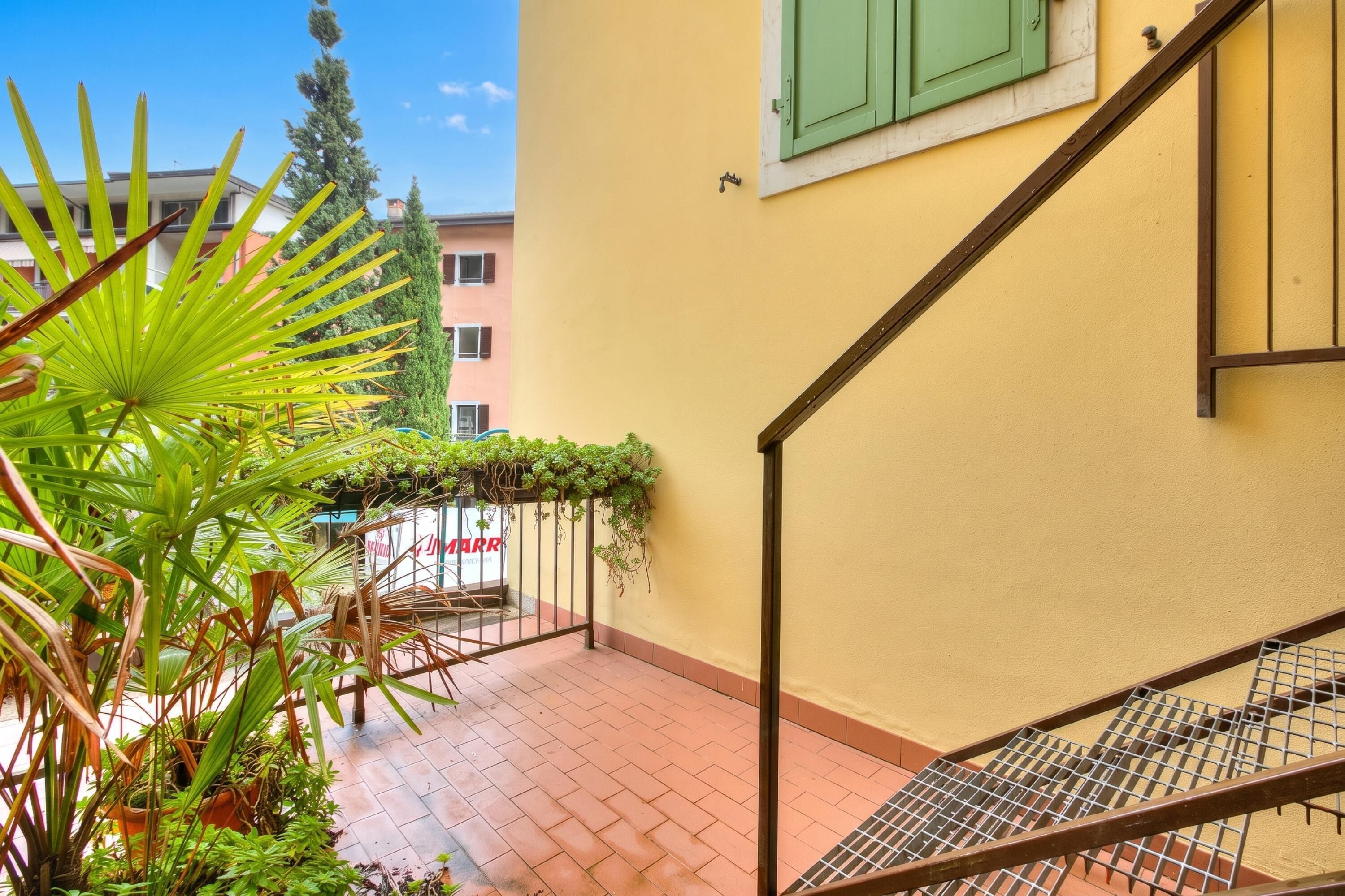 A staircase with a metal railing leading to a yellow wall with a window.