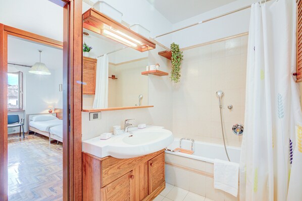 A modern bathroom with a wooden vanity, a large mirror, a shower, and a bathtub.