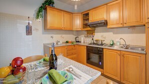 A kitchen with wooden cabinets, a granite countertop, a built-in oven, and a sink. - Lake Garda Home - 3BR With Balcony Views (Riva del Garda)