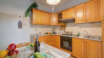 A kitchen with wooden cabinets, a granite countertop, a built-in oven, and a sink.