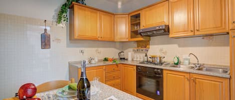 A kitchen with wooden cabinets, a granite countertop, a built-in oven, and a sink.