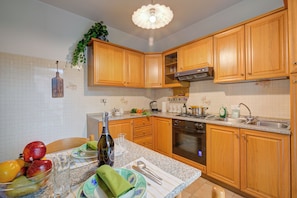A kitchen with wooden cabinets, a granite countertop, a built-in oven, and a sink. - Lake Garda Home - 3BR With Balcony Views (Riva del Garda)