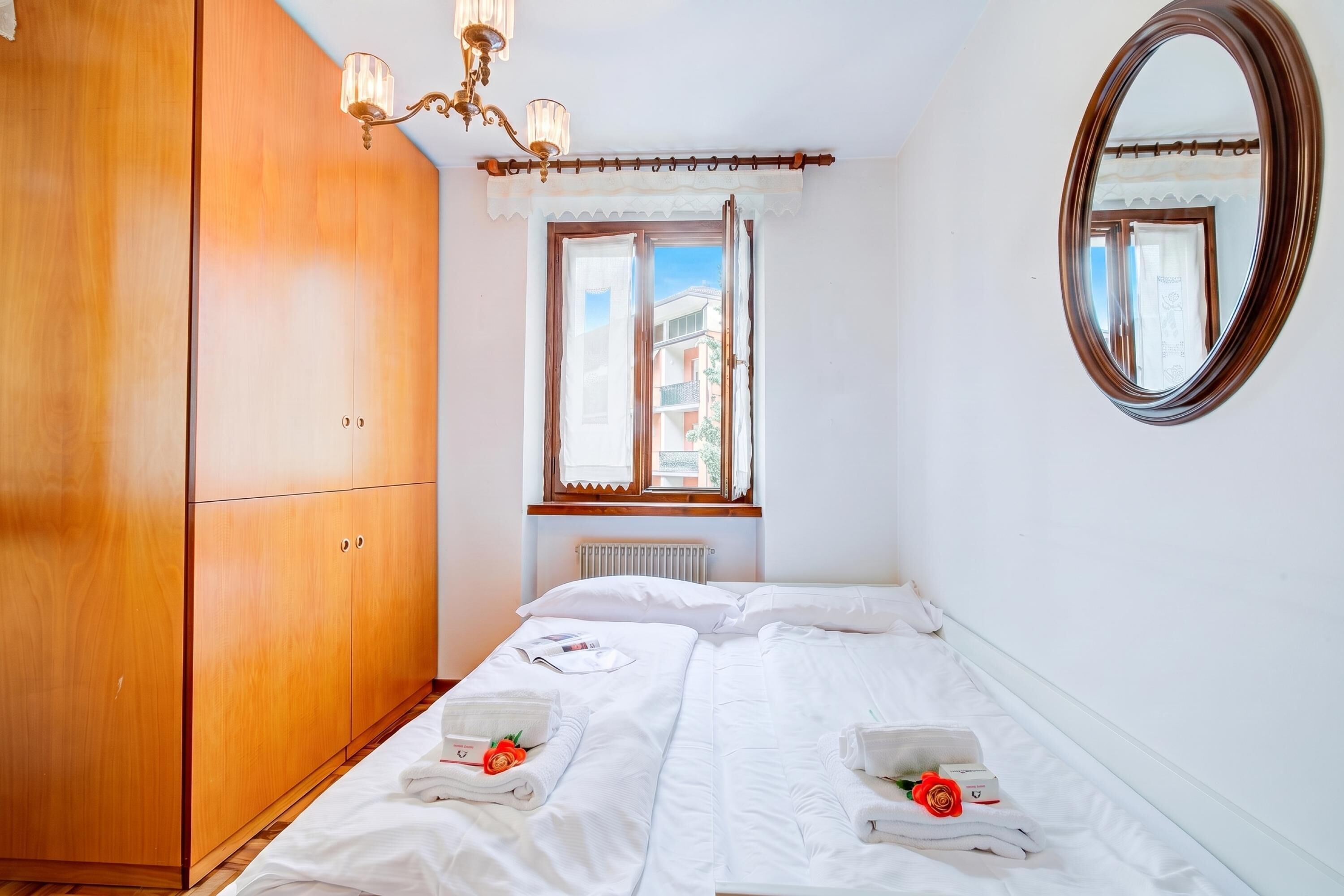 Ett hotellrum med en säng, en garderob, ett fönster med gardiner och en spegel.