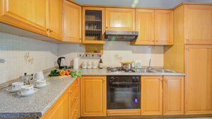 A kitchen with wooden cabinets, a stainless steel stove, and a dishwasher. - Lake Garda Home - 3BR With Balcony Views (Riva del Garda)