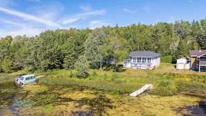 Uma propriedade à beira do lago com casa, píer e barco.