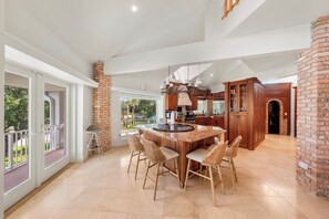 A spacious kitchen with a large island, wooden cabinets, and a view to the outdoors.