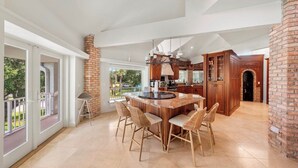 A spacious kitchen with a large island, wooden cabinets, and a view to the outdoors. - 151 Bounty LN - Daytona Beach Oceanfront Vacations, Inc (Ponce Inlet)