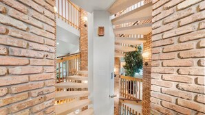 A staircase with brick walls and wooden railings leading to an upper floor. - 151 Bounty LN - Daytona Beach Oceanfront Vacations, Inc (Ponce Inlet)