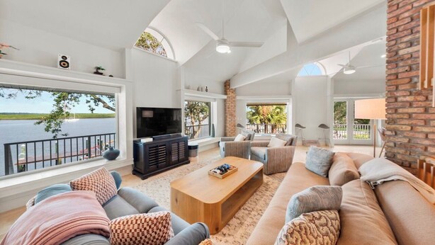 A spacious living room with a large TV, comfortable seating, and a view of the water. - 151 Bounty LN - Daytona Beach Oceanfront Vacations, Inc (Ponce Inlet)