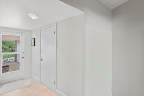 A clean, white-walled hallway with a door leading to a balcony.