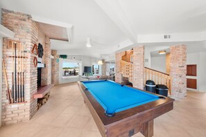 A pool table in a room with brick walls and a wooden bench.