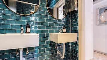 A bathroom with two sinks, a mirror, and a shower.