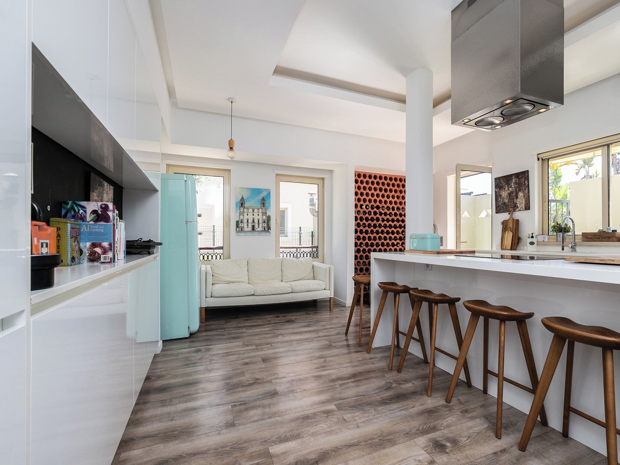 A modern kitchen with white cabinetry, a wooden bar counter, and stools.