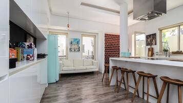 Una cocina moderna con armarios blancos, una barra de madera y taburetes.