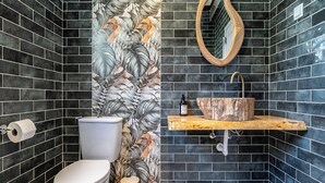 A bathroom with a toilet, a sink with a wooden countertop, and a mirror.