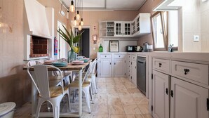 Une cuisine avec des meubles blancs, une table à manger avec des chaises et un luminaire suspendu.