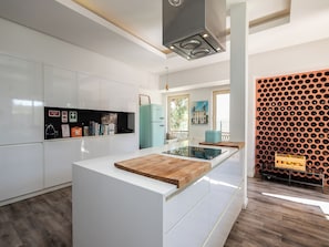 A modern kitchen with white cabinetry, a central island with a wooden countertop, a built-in stove, and a wine rack on the wall. - Walk in Hostel Faro (Faro)