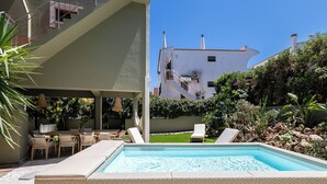 A pool area with lounge chairs, a table, and a covered seating area.